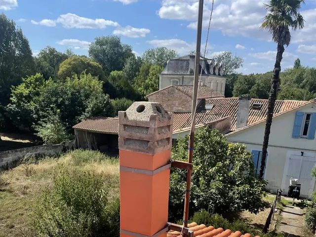 Souche de cheminée neuve avec mitron sur toiture en tuiles canal, vue en plongée — chantier Artisan JP